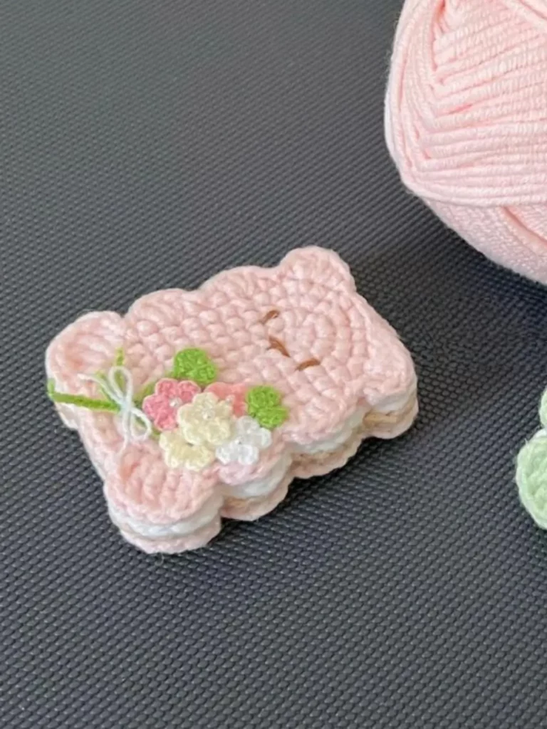 Pink crocheted bear-shaped treat, decorated with flowers.