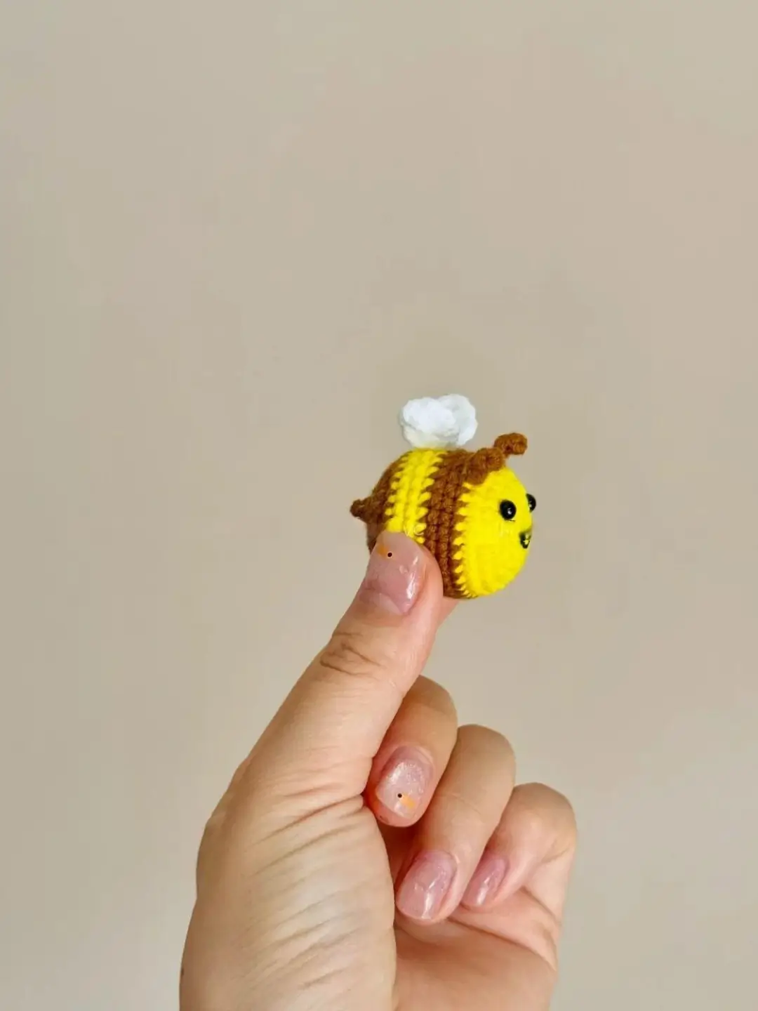 Crocheted bee held by hand.  Yellow and brown bee figurine.