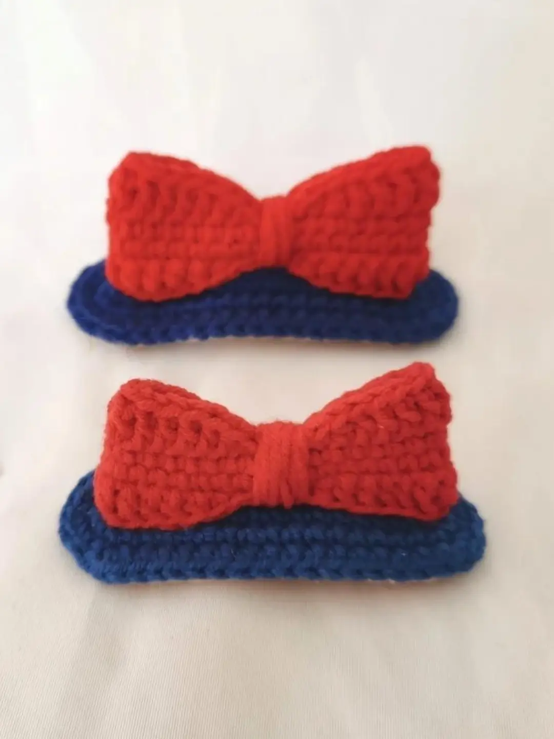 Two red and navy blue crocheted bows.