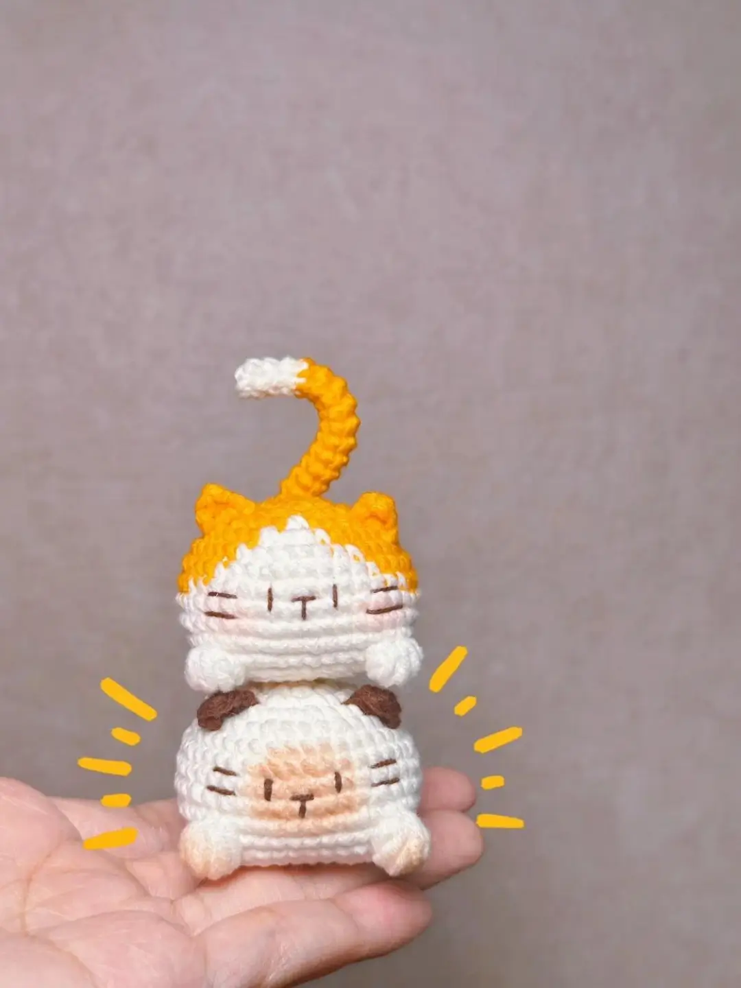 Crocheted cat and sheep amigurumi, stacked, hand held.
