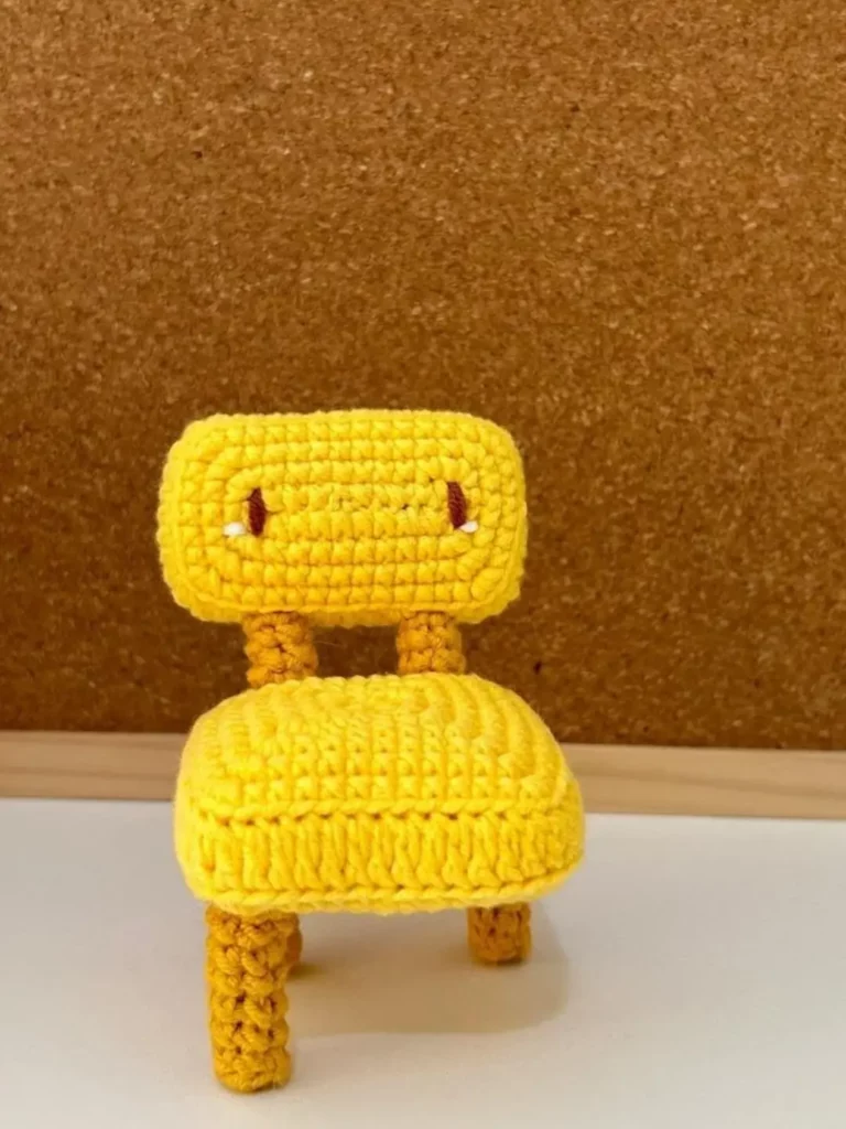 Small crocheted yellow chair with brown accents.
