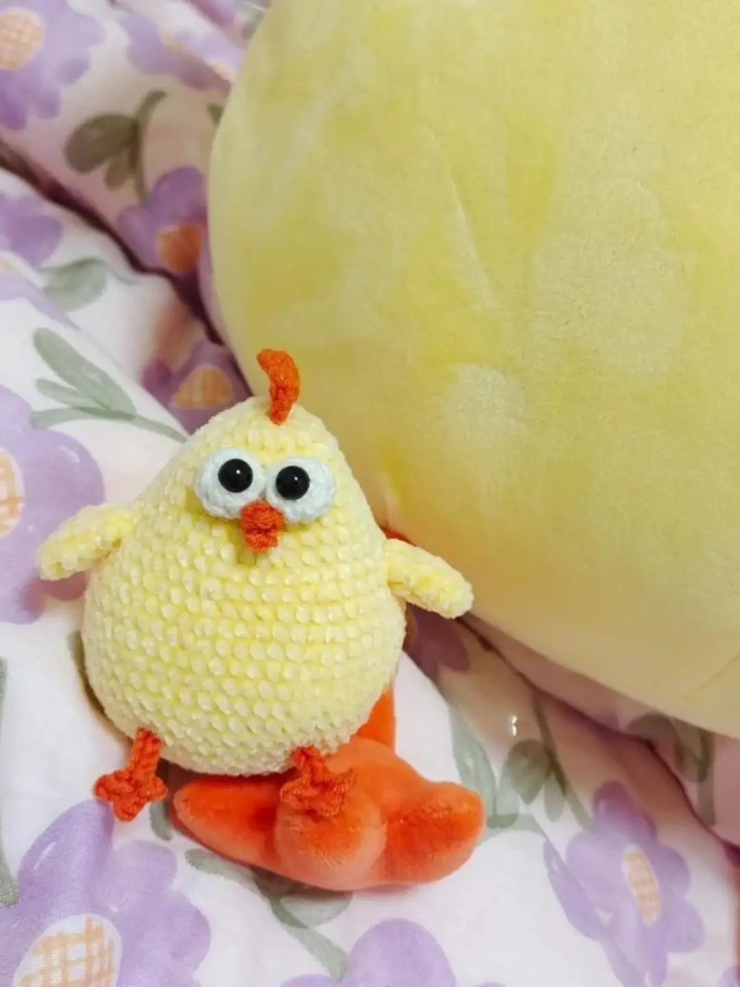 Small yellow crocheted chick toy, orange feet.