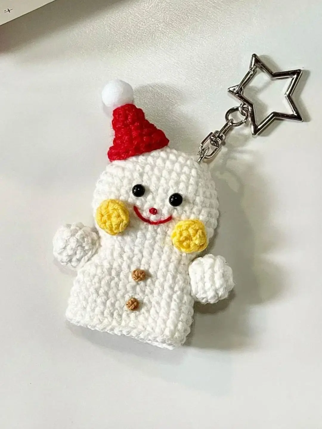 Crocheted snowman keychain, red hat, yellow buttons.