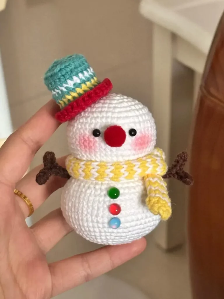 Crocheted snowman with hat, scarf, and colorful buttons.