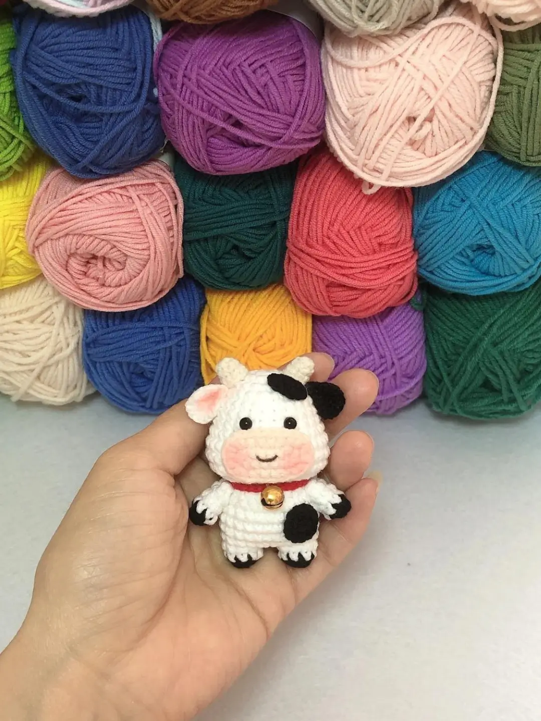 Crocheted cow, colorful yarn background.