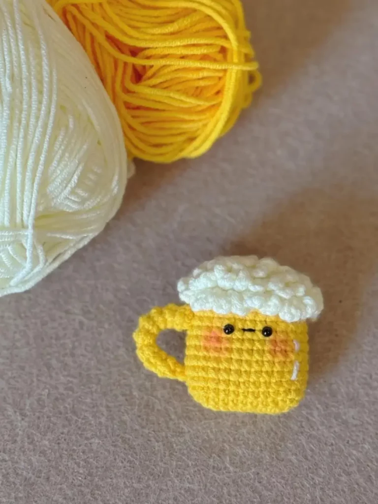 Crocheted yellow beer mug, yarn balls.