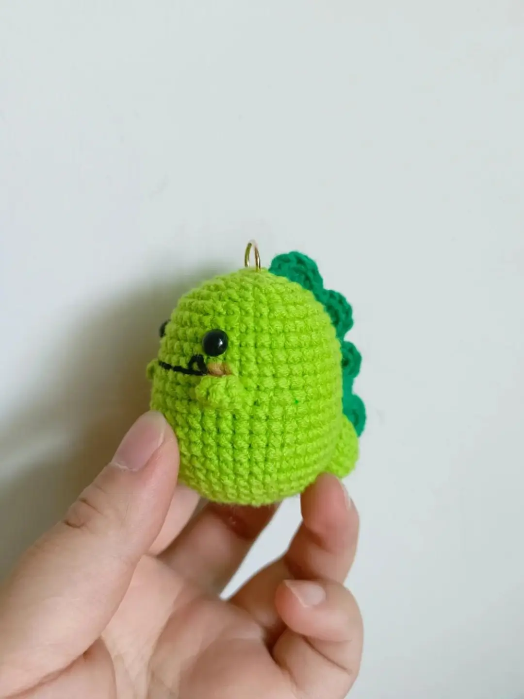 Crocheted green dinosaur keychain.