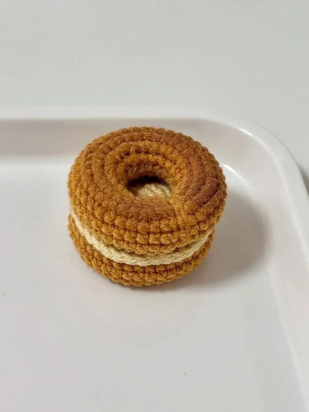 Crocheted  donut, caramel-colored, cream filling.