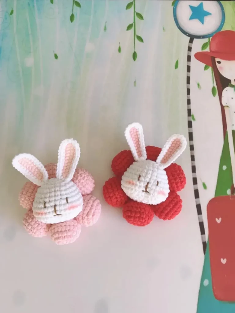 Two crocheted bunny flower brooches, pink and red.
