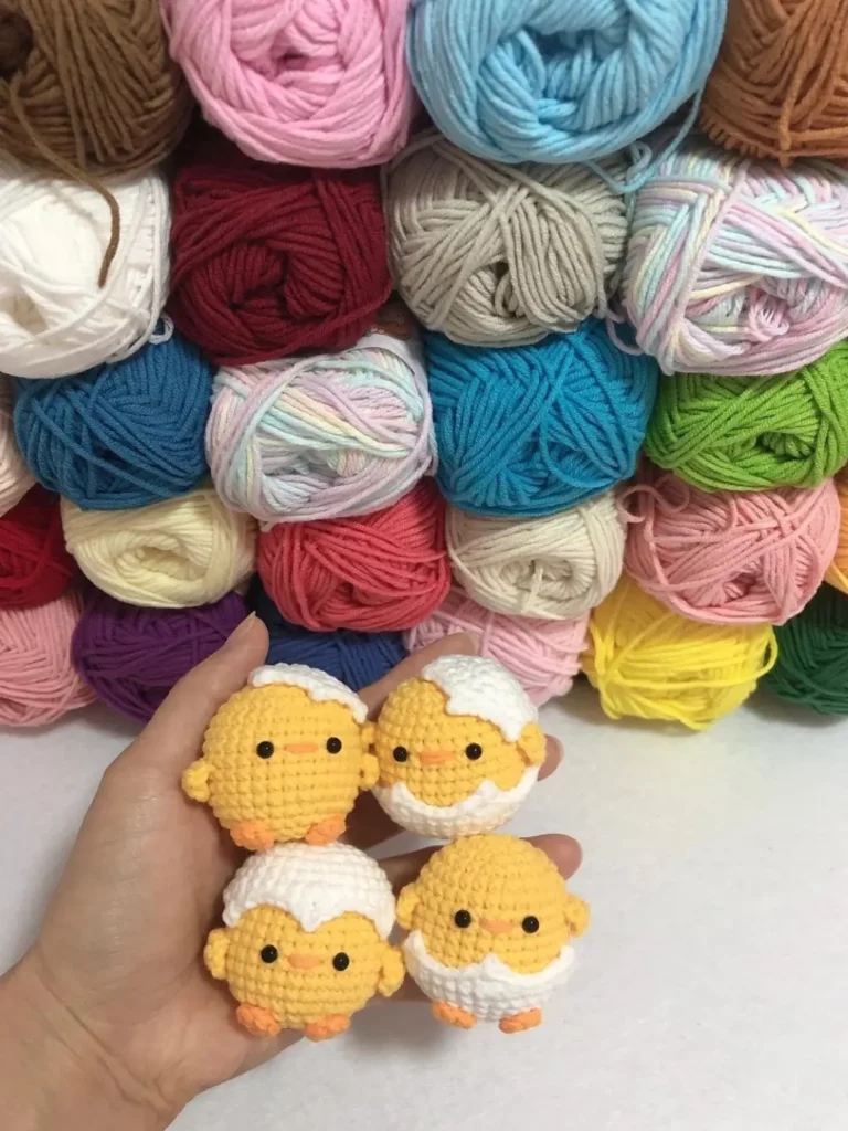 Cute crocheted baby chicks, yarn balls background.