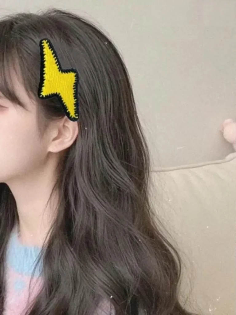 Yellow lightning bolt hair clip on woman's dark brown hair.