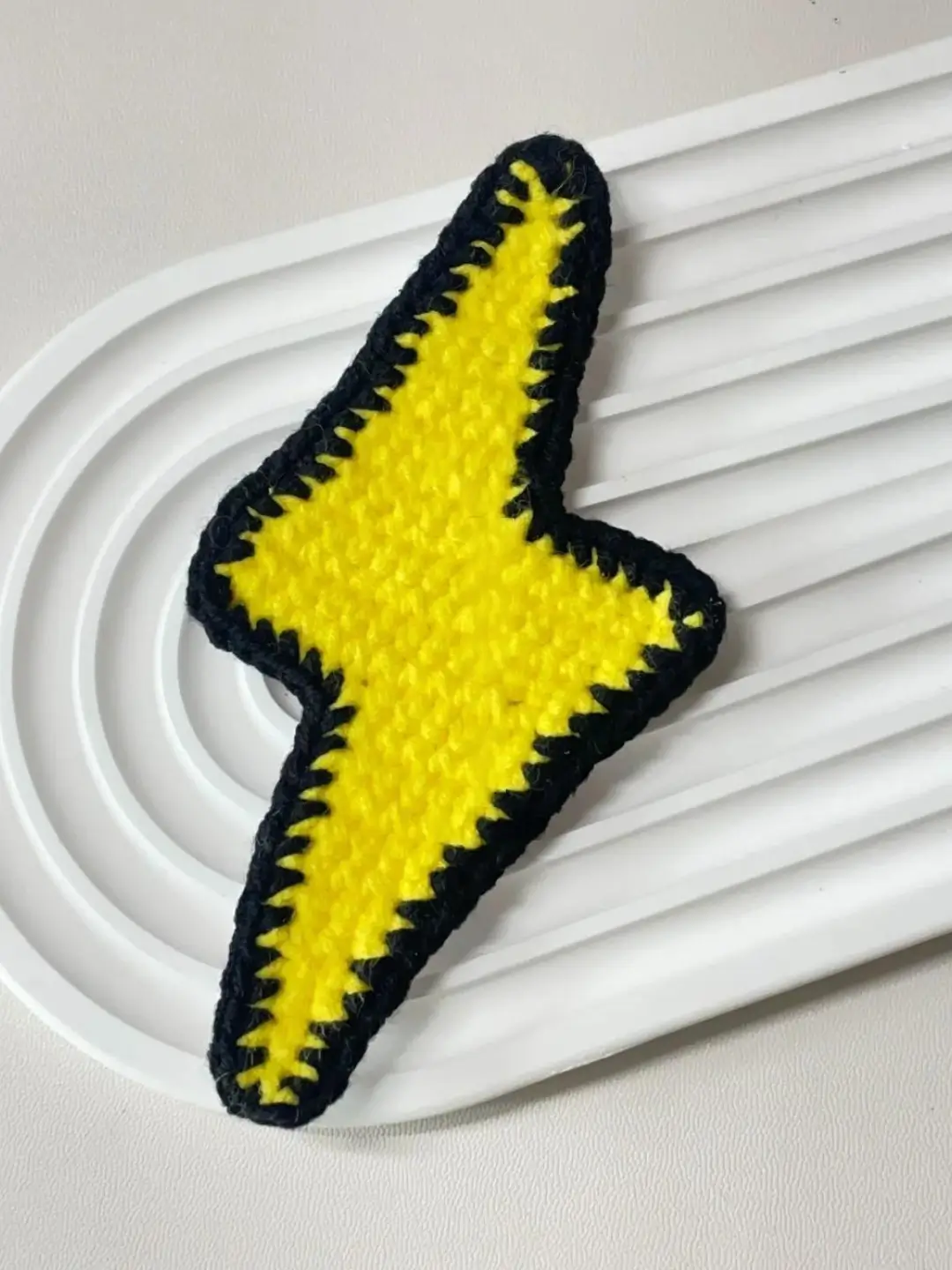 Crocheted yellow lightning bolt with black trim.