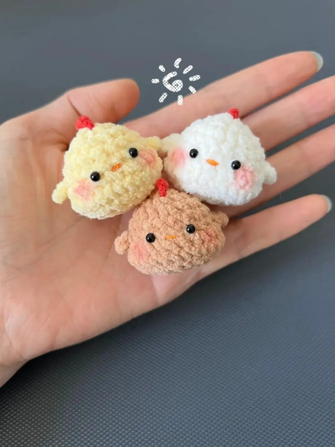 Three small crocheted chicken amigurumi, yellow, white, and tan.