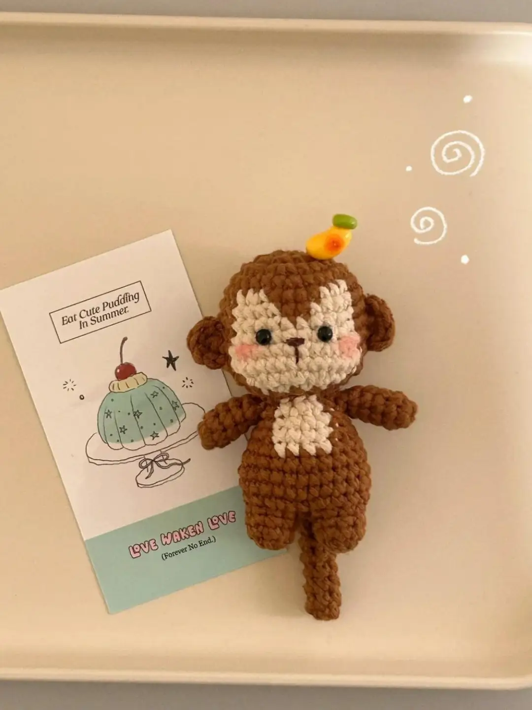 Crochet monkey figurine, brown, banana on head.