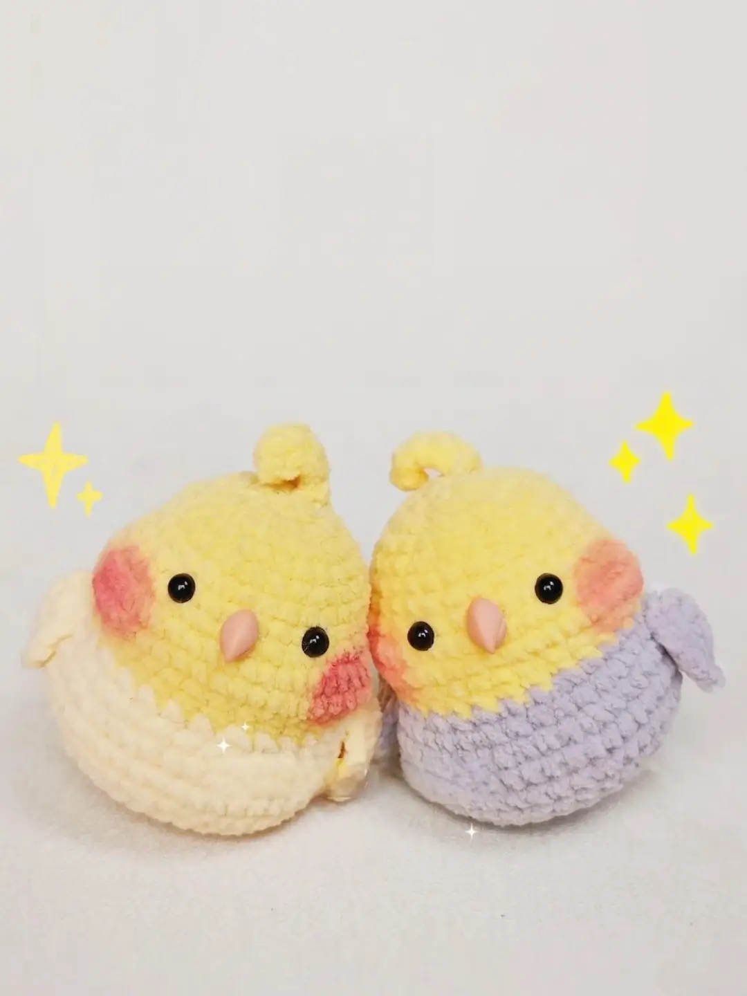 Two crocheted parakeets, yellow and lavender, cute plush toys.