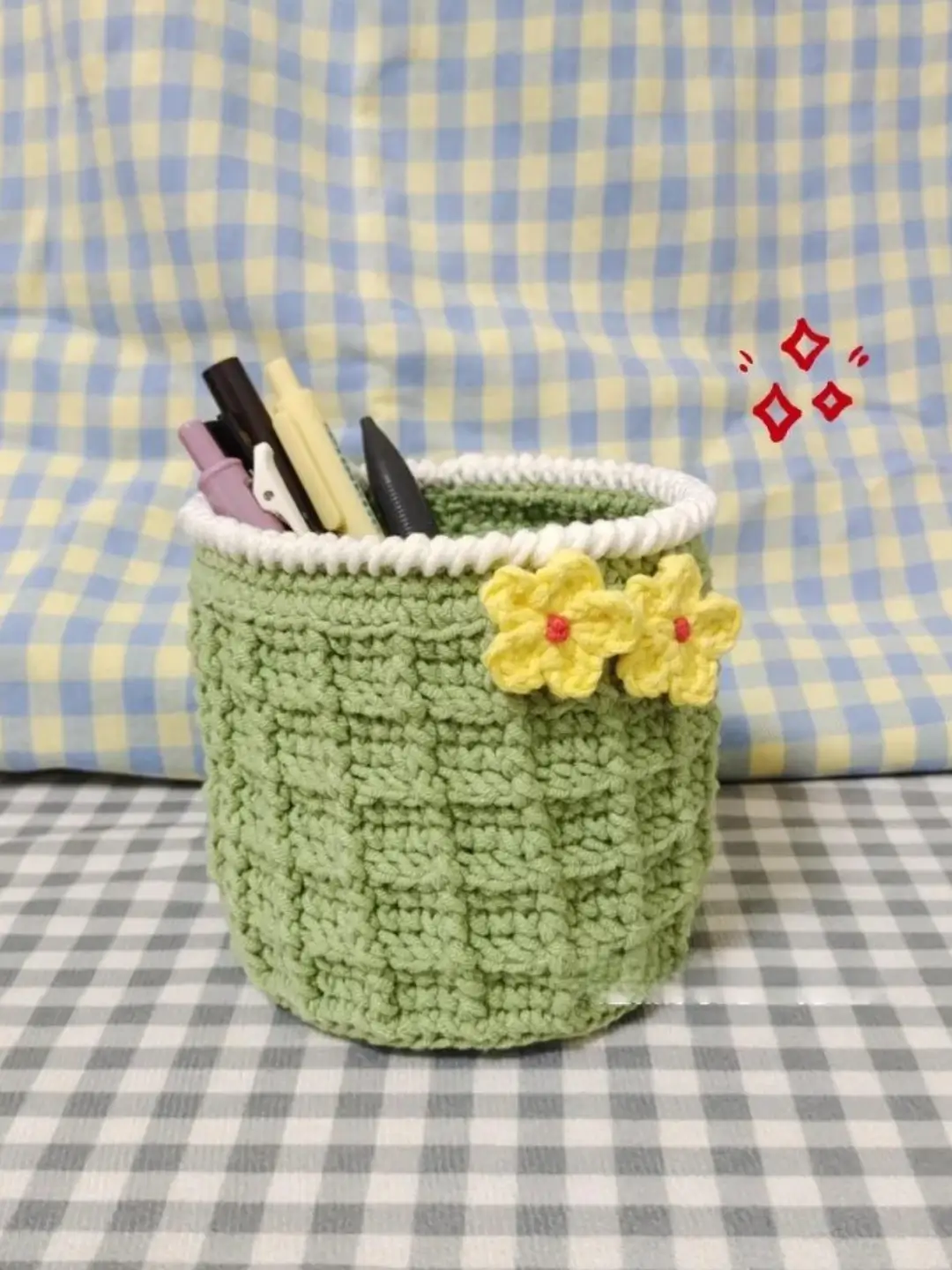 Light green crocheted pencil holder with yellow flowers.