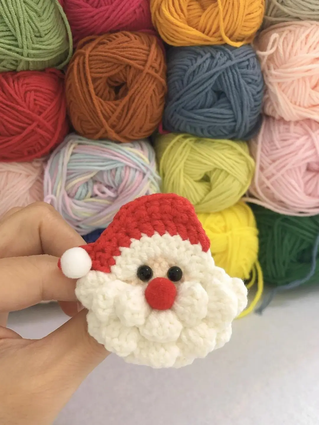 Crocheted Santa Claus, colorful yarn balls background.