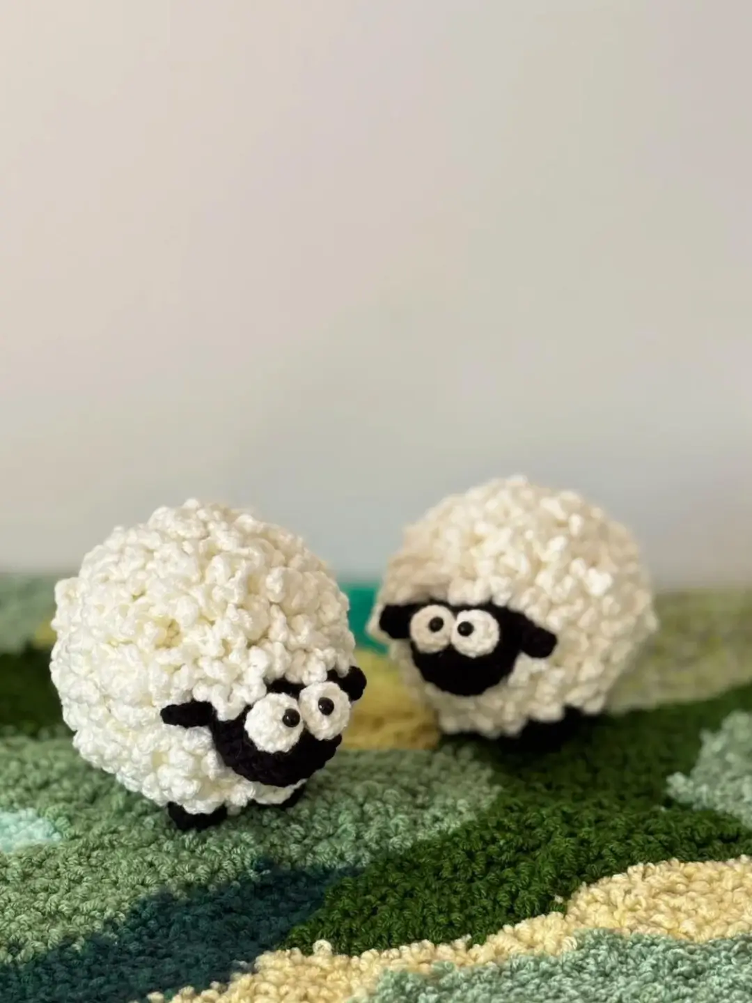 Two crocheted sheep on a textured rug.
