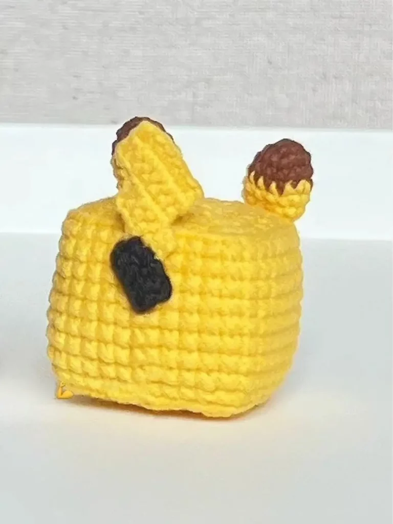 Yellow crocheted plush toy, dark brown ears.