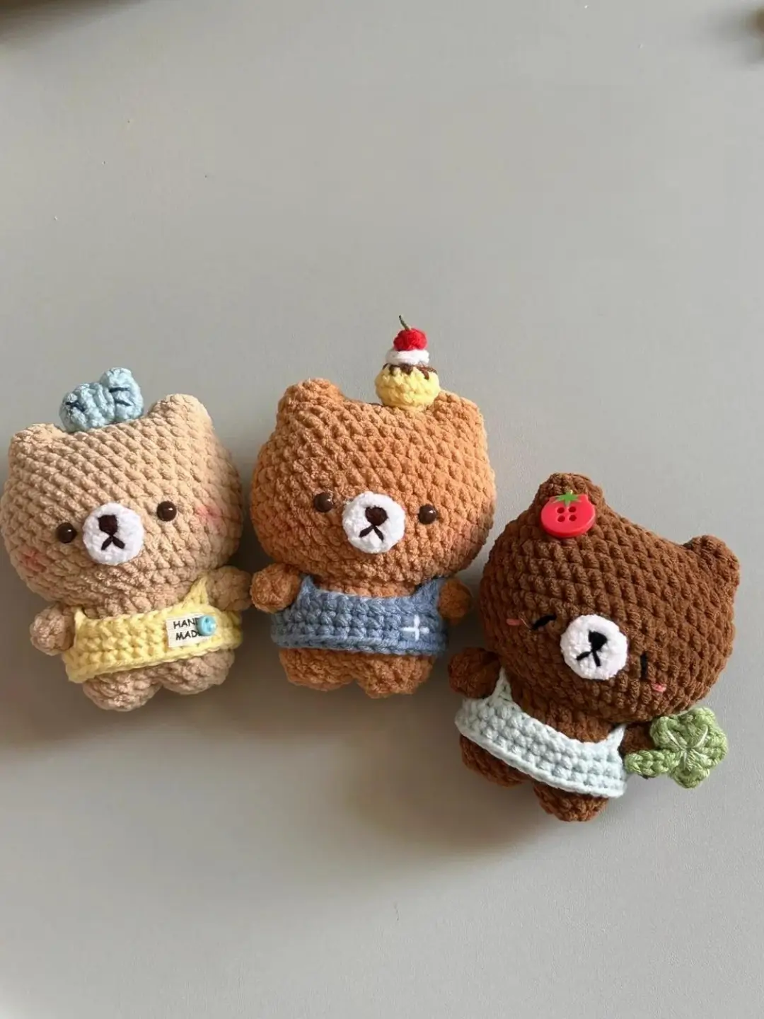Three crocheted bear toys, pastel colors,  cute faces.