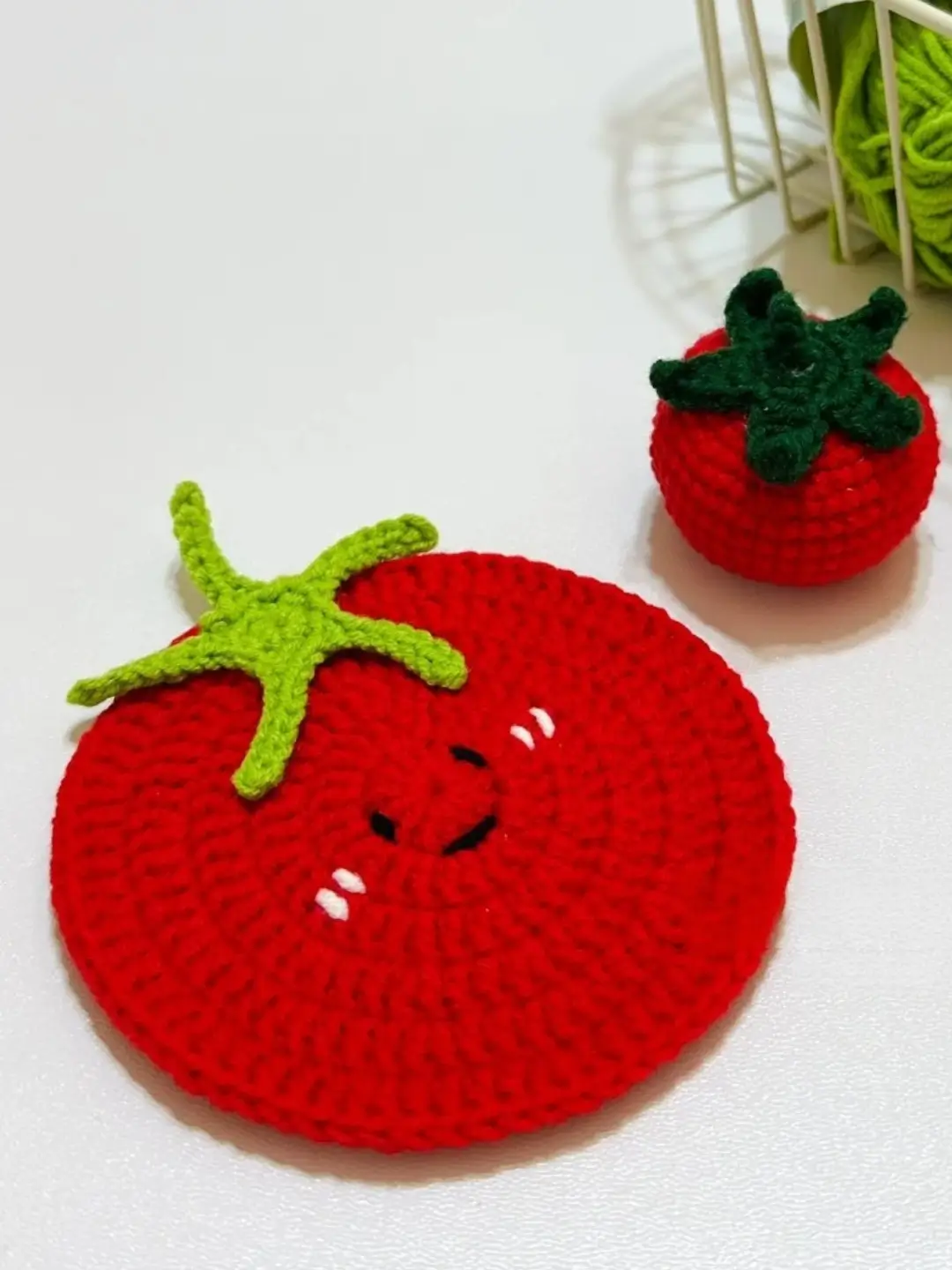 Crocheted red tomato with green stem, cute face.